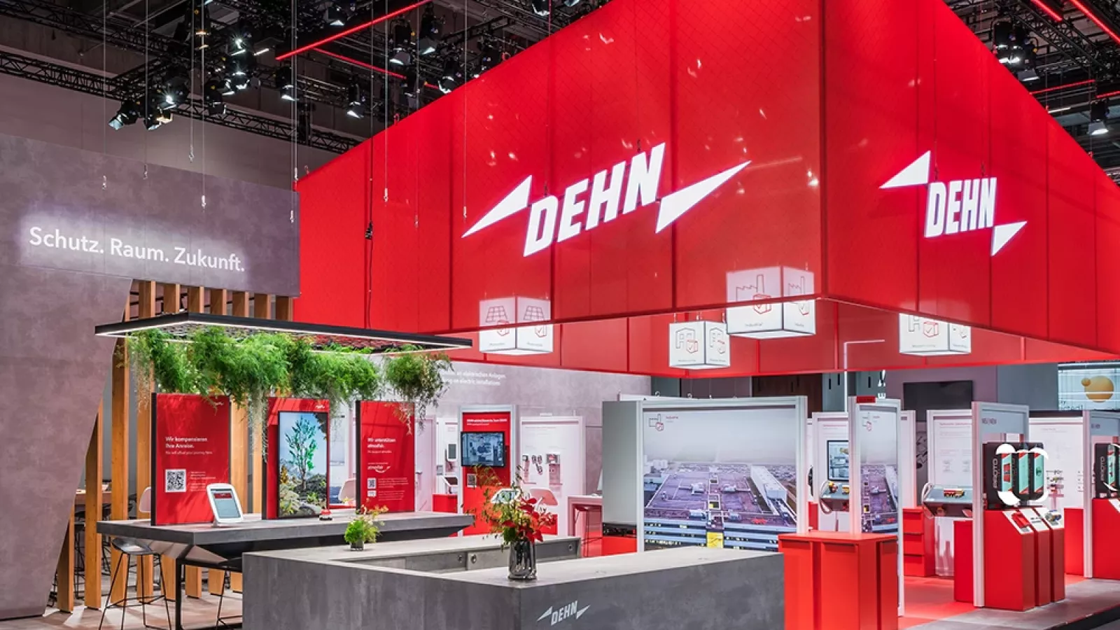 Trade fair booth with large red DEHN cube, illuminated logo, exhibition counters, displays, and visible text “Schutz. Raum. Zukunft.”