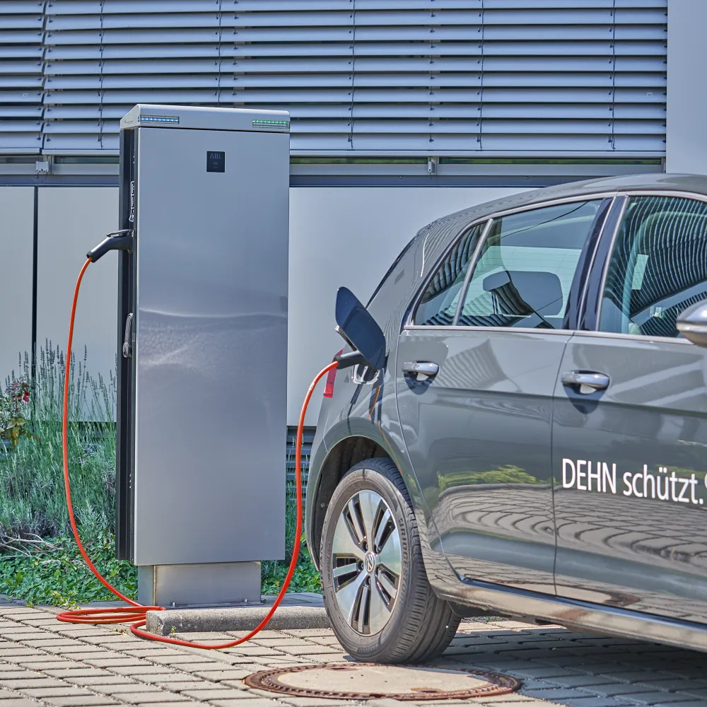 Graues Elektrofahrzeug, das an einer Ladestation mit einem orangefarbenen Ladekabel geladen wird.