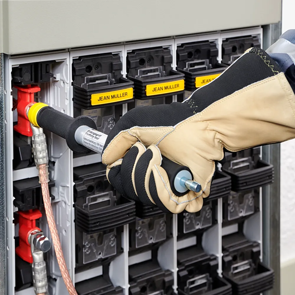 Close-up of a gloved technician connecting a grounding tool to a fuse switch in an electrical distribution cabinet with labeled modules.