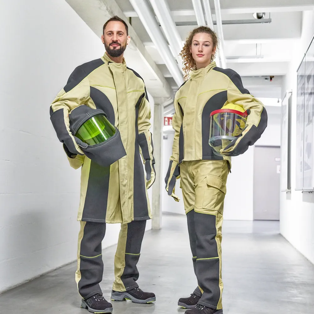 Two electricians in protective workwear stand in an industrial corridor, holding helmets with visors as part of modern personal protective equipment.