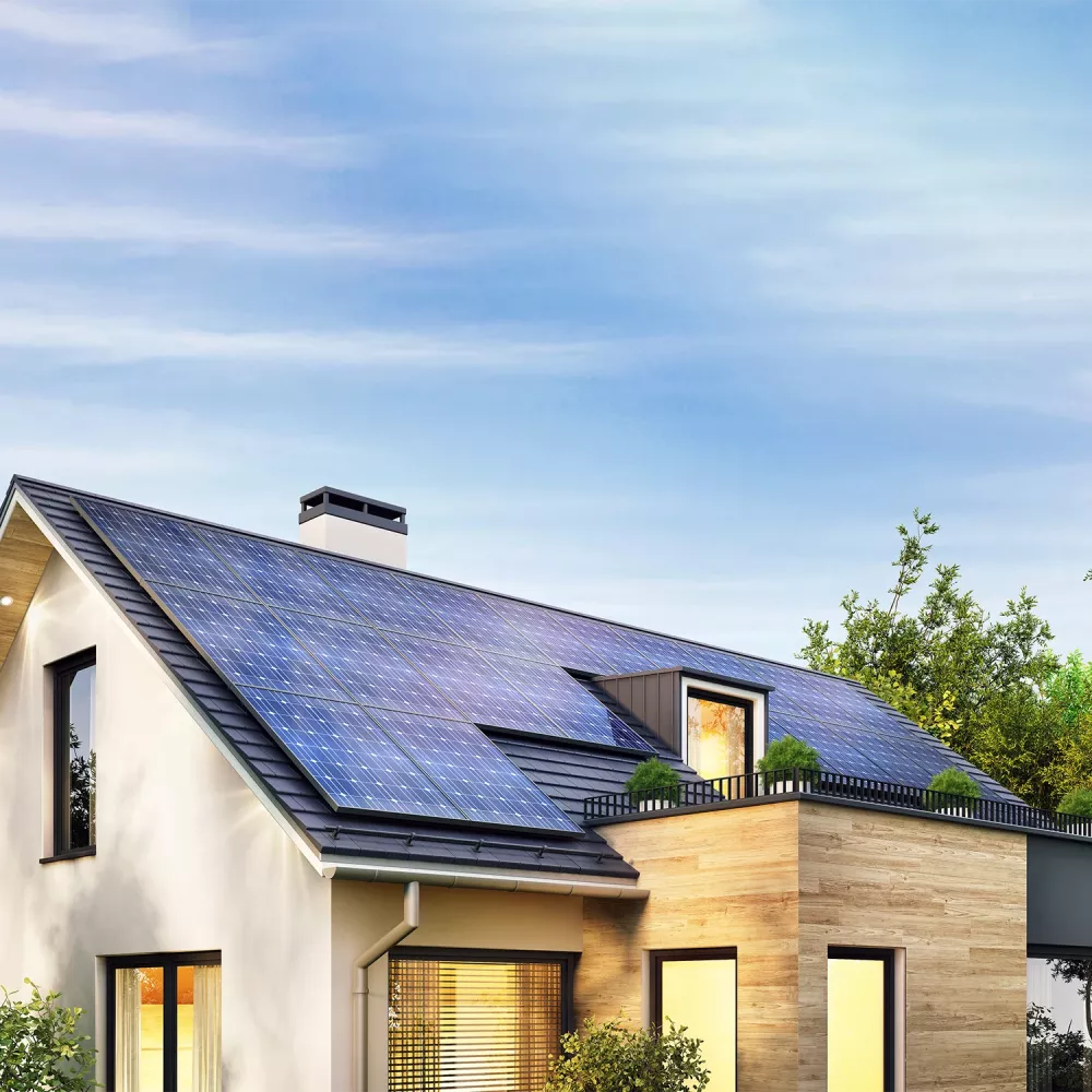 Modern single-family house with rooftop solar panels, large windows, and surrounding trees under a clear blue sky.