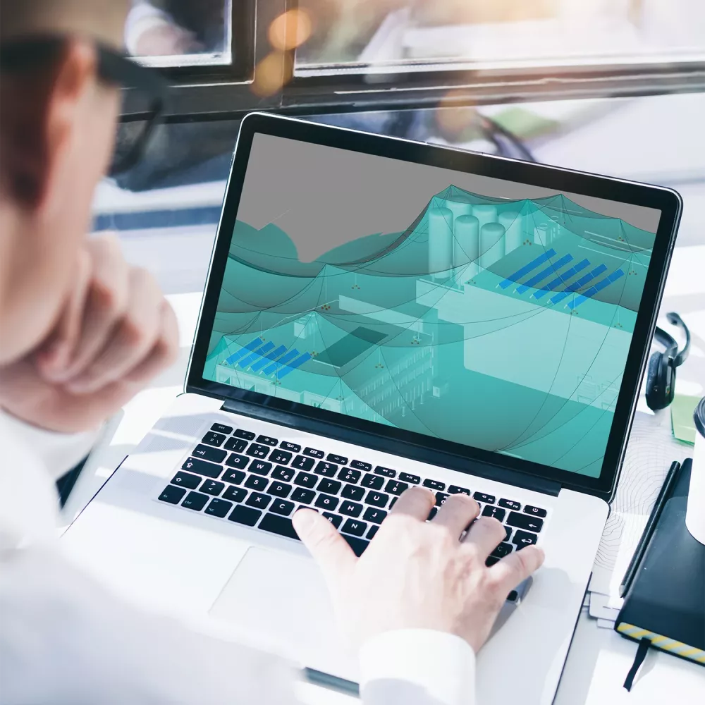 Laptop screen showing electrical planning software with a 3D protection zone model while a person works at the keyboard.