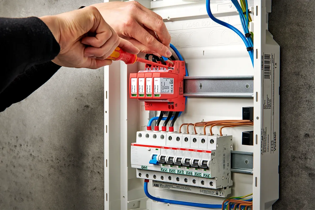 Elektriker installiert Überspannungsschutz in einem Sicherungskasten.
