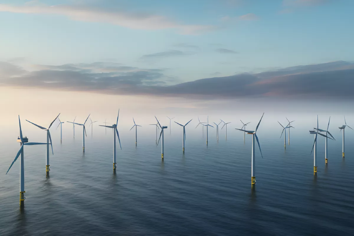 Group of offshore wind turbines standing in calm sea under a partly cloudy sky.